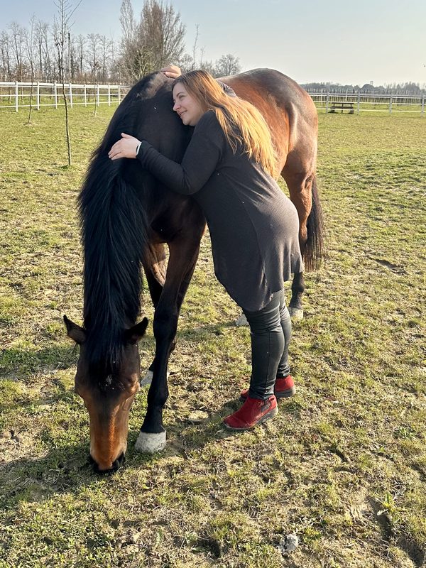 Abbraccio tra una persona e il cavallo al pascolo